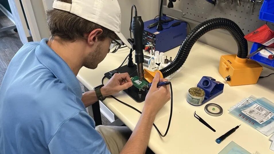An engineer soldering electronics at a LlamaWorks lab workbench